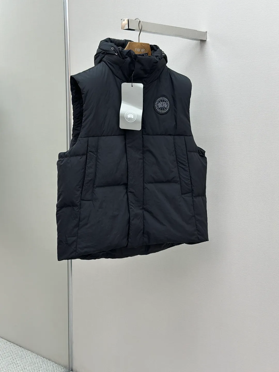 P760 Canada Goose logo hooded down vest Fabric selection: The use of high-quality protective nylon fabric not only enhances the wear resistance of the surface, but also takes into account wind resistance, ensuring excellent performance in various harsh weather conditions.  90 national standard high-quality white duck down: selected high-loft down, weighing 170g, light and warm, with excellent temperature locking performance and good resilience.  Three-dimensional quilting process: Precision thread reinforcement to prevent velvet drilling and ensure that the fluffy and resilient elasticity lasts as new.  Details: Use polyester as the base for woven webbing, and use high-precision computer embroidery to decorate the brand letters on the webbing. The edges of the pattern are clear, the stitches are fine and even, and multiple layers of embroidery threads are stacked to enhance the three-dimensional effect. Accessories: Customized logo Customized zipper pendant Customized hem elastic buckle Customized snap button SIZE: S M L XL